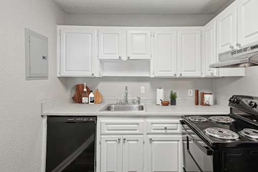 Sandy Springs, GA Apartments – Celebration at Sandy Springs – A white kitchen with a black dishwasher and stove.