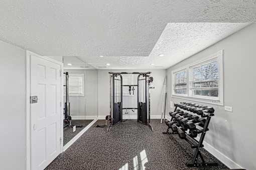 Sandy Springs, GA Apartments – Celebration at Sandy Springs – gym with a variety of equipment including a squat rack, bench, and dumbbells.