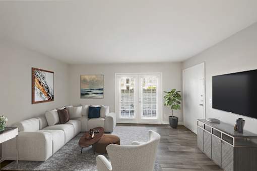 Apartments in Sandy Springs Georgia for Rent – Celebration at Sandy Springs - A living room with a white couch, a brown chair, a coffee table, a television, and a painting on the wall.
