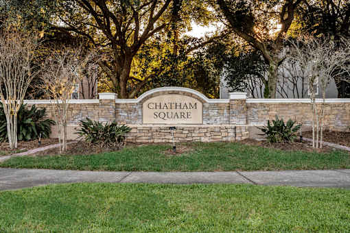 A sign that says Chatham Square is in front of some trees.