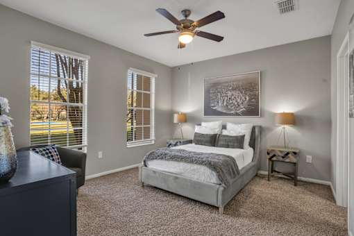 A bedroom with a bed, a dresser, and a ceiling fan.