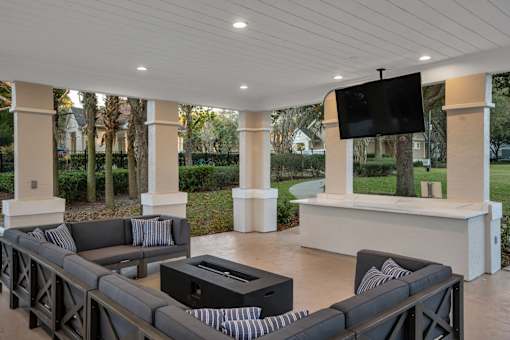A modern outdoor living room with a television and comfortable seating.