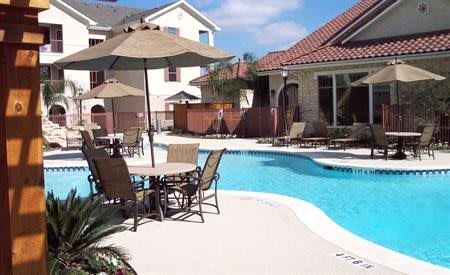 A pool with chairs and umbrellas in front of a house.