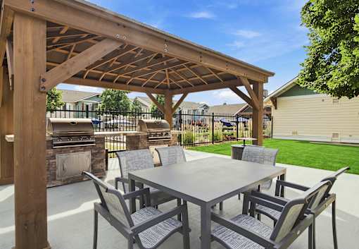 A wooden pergola with a table and chairs underneath it.