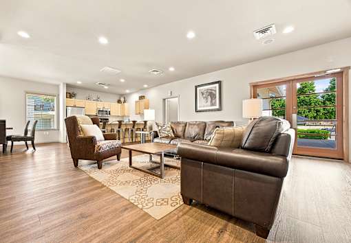 A living room with a brown couch and a rug.