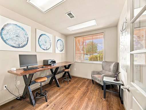 A room with a desk, chair, and two paintings on the wall.