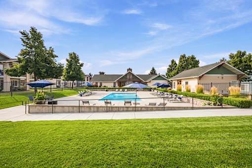A sunny day at a community pool with a few people relaxing.