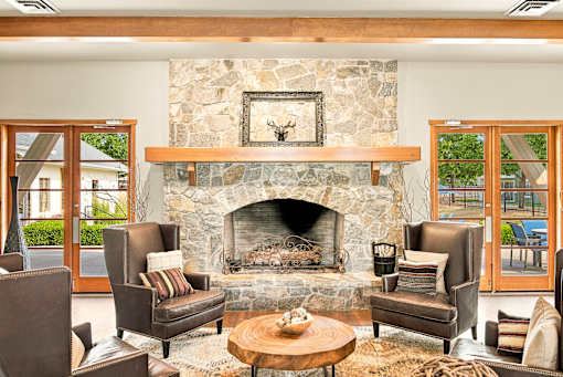 A living room with a stone fireplace and a picture of a deer above it.