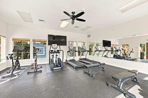 A spacious gym with a variety of equipment including treadmills, stationary bikes, and weight machines.