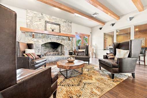 A living room with a stone fireplace and wooden beams.