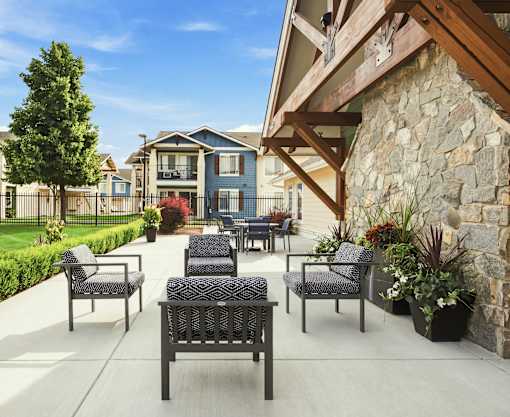A patio with a table and chairs is in front of a house.