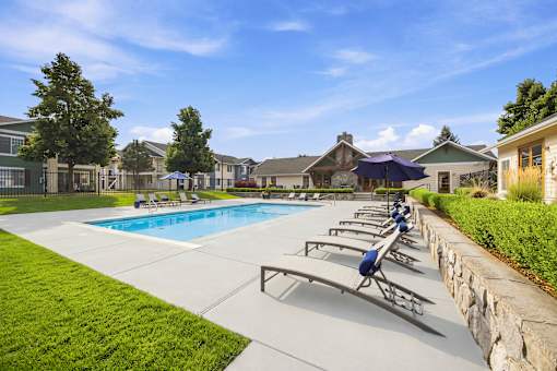 A swimming pool with sun loungers and a stone wall.