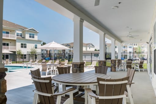 Clubhouse pool deck with tables and chairs under covered area