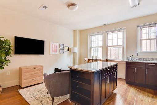 A kitchen with a black counter top and a grey chair.