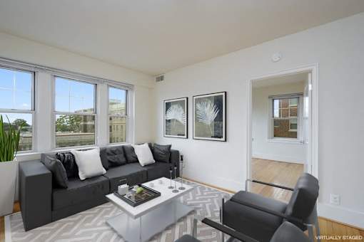 A living room with a grey couch, a coffee table, and two framed pictures on the wall.