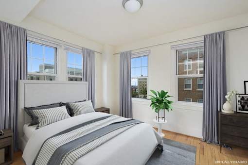 A bedroom with a large bed and a window with a view of a building outside.