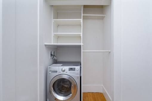 A washing machine is built into a wall in a small room.