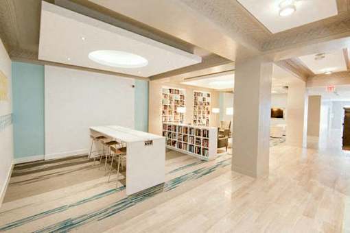 A room with a long table and chairs and a bookshelf with books.