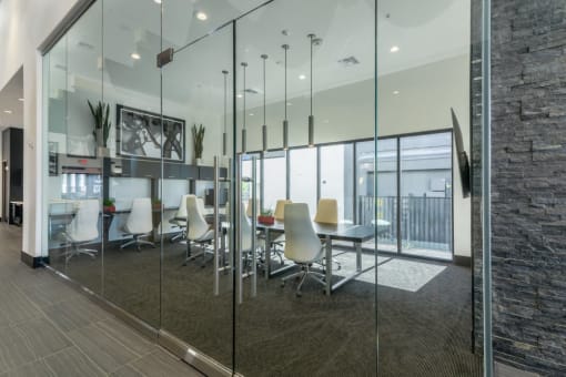 an conference room with a tv and glass walls and a table and chairs