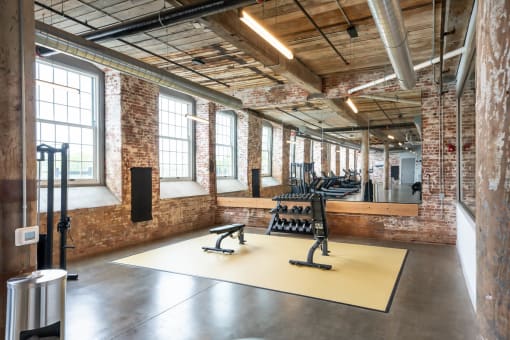 the gym has large windows and a yellow floor with weights on it
