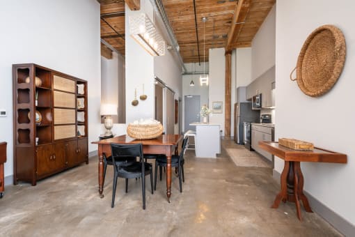 a dining room with a wooden table and chairs and a kitchen in the background