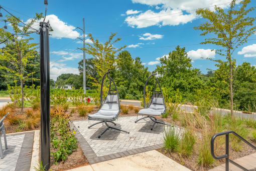 two lounge chairs on a patio in a park with trees