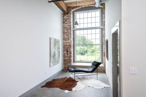 a leather chair sits in front of a window in a white room