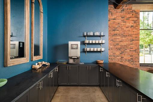 A kitchen with dark blue walls and black countertops.