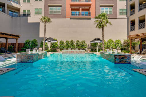 A swimming pool in front of a building with palm trees.