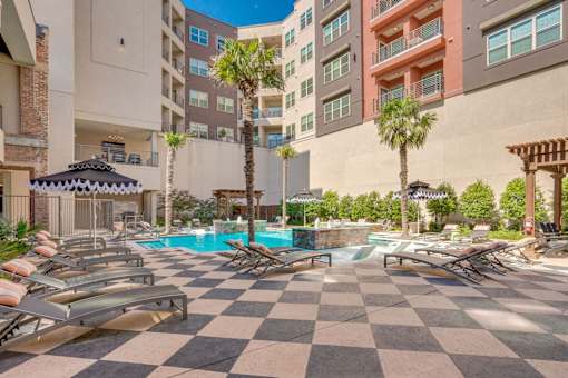 A pool surrounded by lounge chairs and umbrellas.