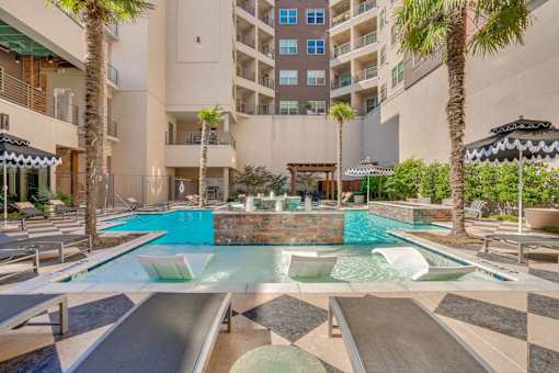 A large outdoor pool with a slide and a hot tub.