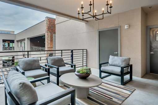 A patio with a table, chairs, and a hanging light fixture.