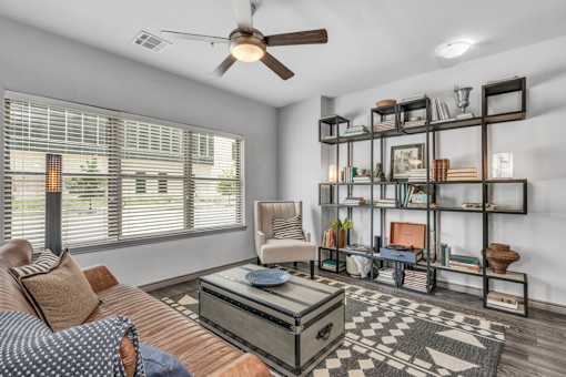A living room with a brown couch, a coffee table, and a ceiling fan.