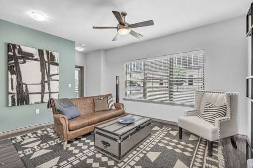 A living room with a brown couch, a coffee table, and a ceiling fan.
