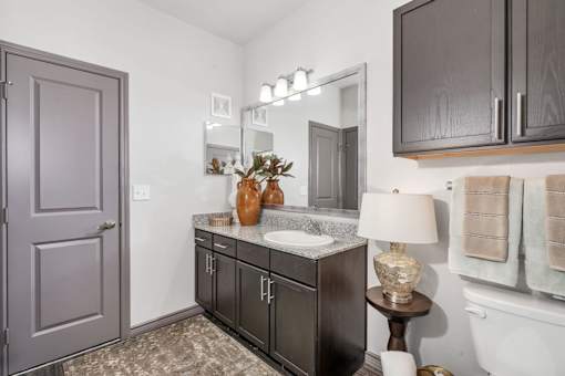 A bathroom with a sink, mirror, and towel rack.