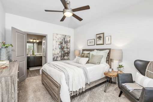 A bedroom with a large bed, a chair, and a ceiling fan.