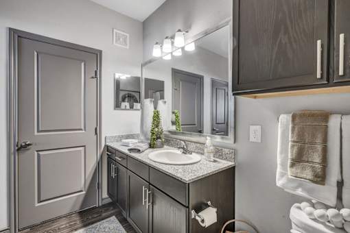 A bathroom with a sink, mirror, and towel rack.
