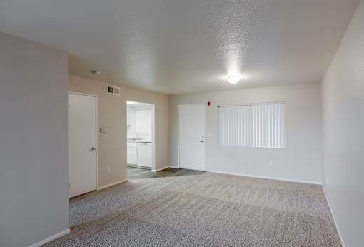 the living room of an apartment with carpet and a door to the bathroom