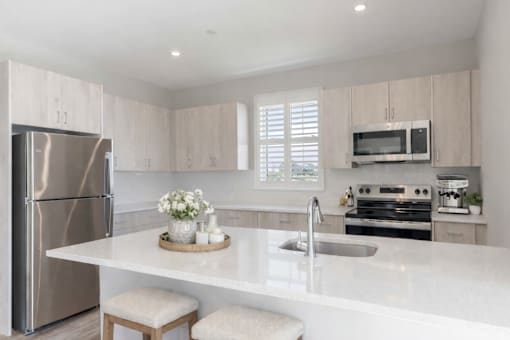 Open-concept kitchen featuring quartz-style countertops, large island seating area, and stainless steel appliances at Creekline at Fairfield apartments, Fairfield CT.