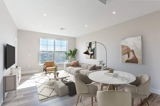 Open-concept living and dining area at Creekline at Fairfield Apartments in Fairfield, CT with large windows, modern furnishings, natural light, and wood-style flooring.