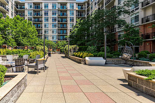 A patio with a table and chairs is surrounded by trees and buildings.