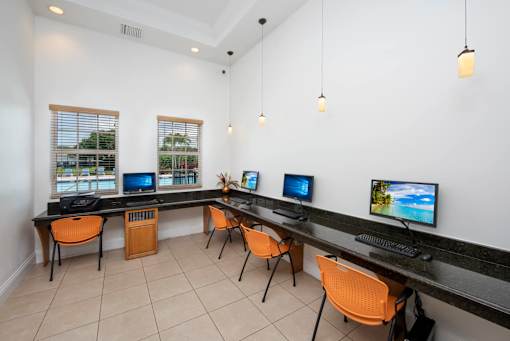 A room with a long desk and chairs with computers on it.