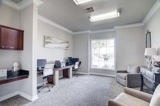 A well-lit office space with a desk, chairs, and a couch.