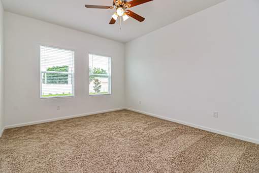 A room with a ceiling fan and carpeted floor.