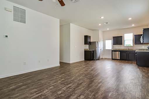 A spacious kitchen with dark wood floors and modern appliances.