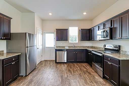 A kitchen with dark wood cabinets and stainless steel appliances.