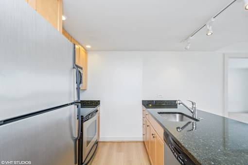 A kitchen with a black granite countertop and stainless steel appliances.