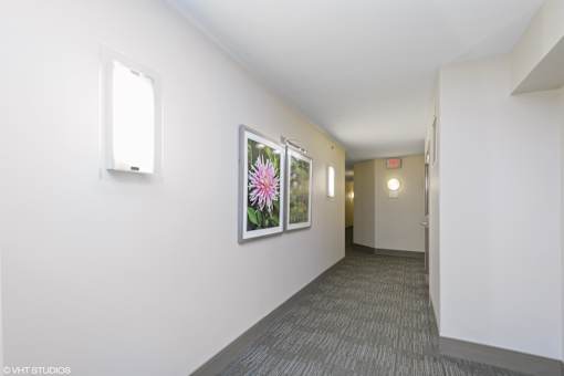 A hallway with a flower picture on the wall and a door on the right.