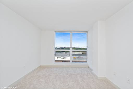 A large empty room with a window overlooking a parking lot.