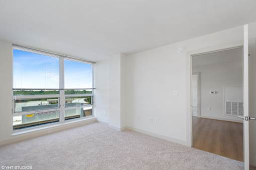 A large empty room with a view of a parking lot through a window.